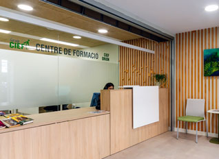 Recepción de la sede de Barcelona con mostrador de madera y cartel "Centre de Formació"