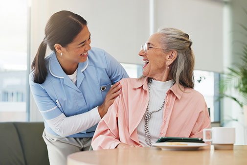 Professional sociosanitària somrient i atenent una dona gran en un entorn assistencial