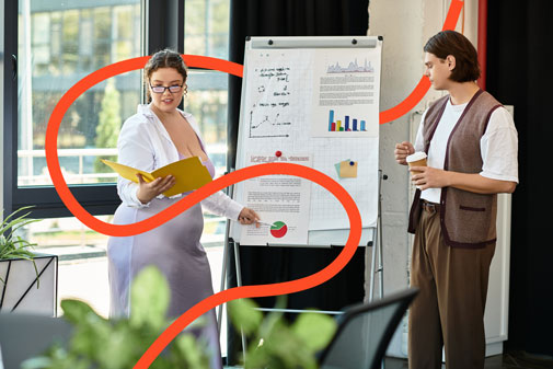 Dos professionals revisant gràfics i dades financeres en una pissarra durant una sessió de treball