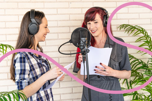 Dues dones practiquen tècnica vocal amb micròfon i auriculars en un estudi de gravació.